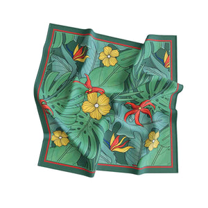 Folded green fabric with tropical leaf and flower pattern on a white background