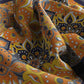 Close-up of patterned fabric with orange, yellow, and black colors.